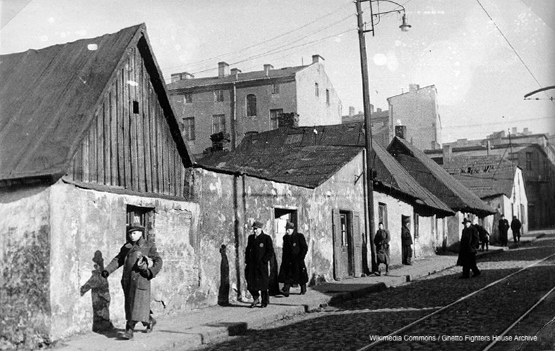 Photograph of Jews on a street in Bedzin, wearing the Jewish badge; from a Nazi German propaganda film