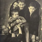 Photograph of Sidney Finkel passing Gad Josef to his older brother as they arrive in Windermere in August 1945.