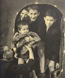 Photograph of Sidney Finkel passing Gad Josef to his older brother as they arrive in Windermere in August 1945.